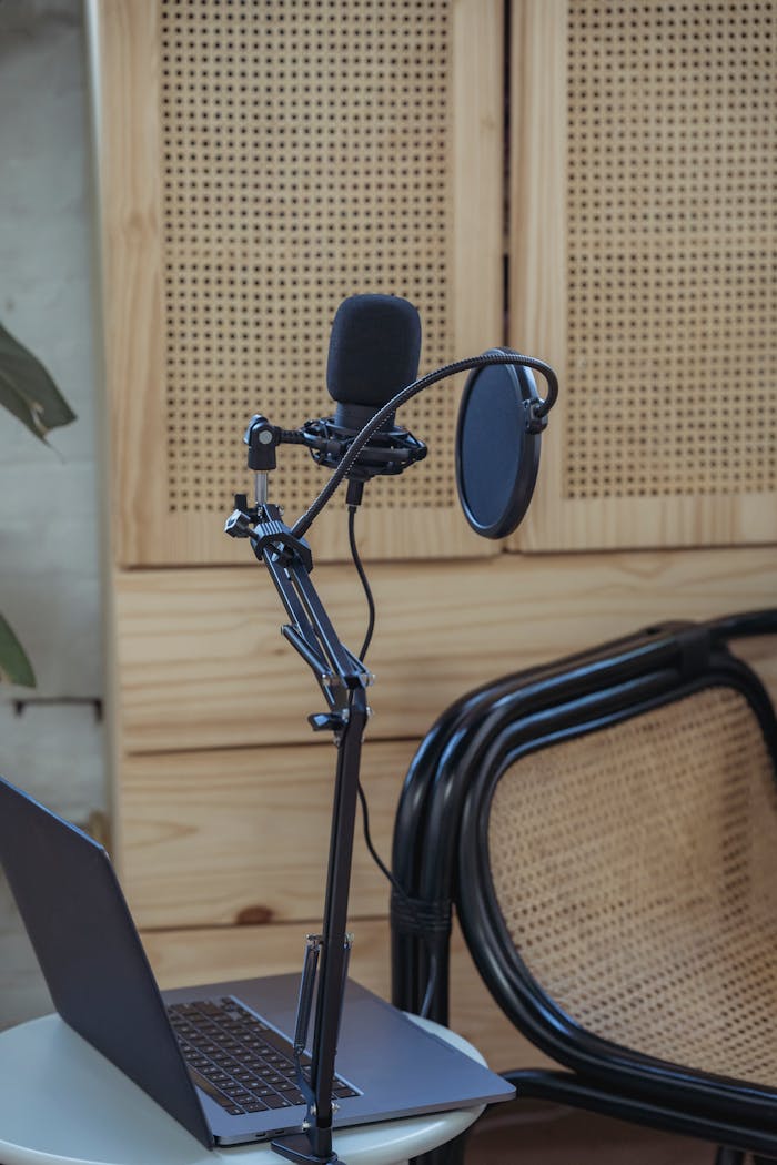 Opened netbook placed on table near tripod with microphone during podcast recording in cozy studio